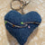 Blue denim keychain with floral embroidery on a textured beige background_Transmutation-keychain.