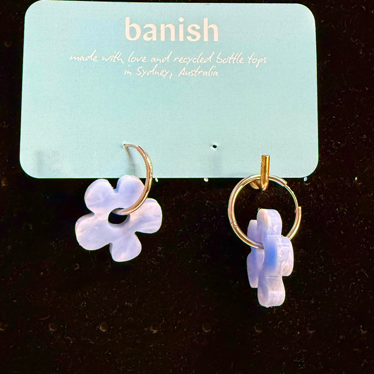 Transmutation - Earrings on gold hoops. Blue and white recycled plastic bottle tops look like clouds. 