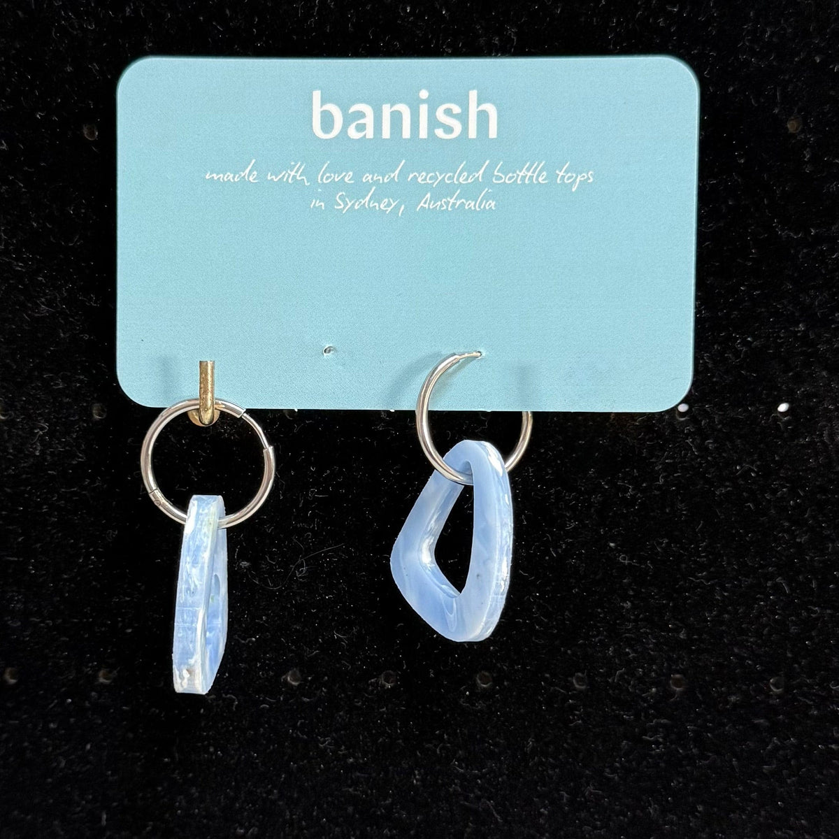 Transmutation - Earrings in a soft blue colour shaped like a sail. Made by recycling plastic bottle tops.