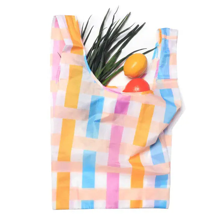 Transmutation-a yellow blue pink and white striped tote made from recycled-rPET showing vegetables in the bag.