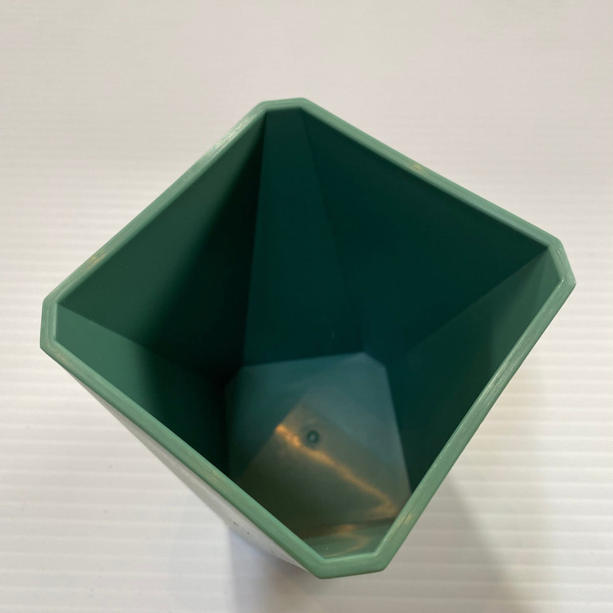 Recycled plastic pot has a geometric design and coloured sage green. Transmutation
